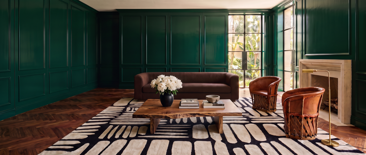 Sala con muros verde esmeralda, equipales, mesa de parota y tapete Stones